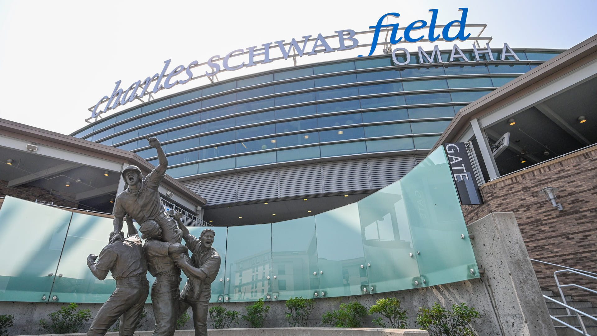 Charles Schwab Field Omaha sign above the stadium entrance, with the bronze player statue out front