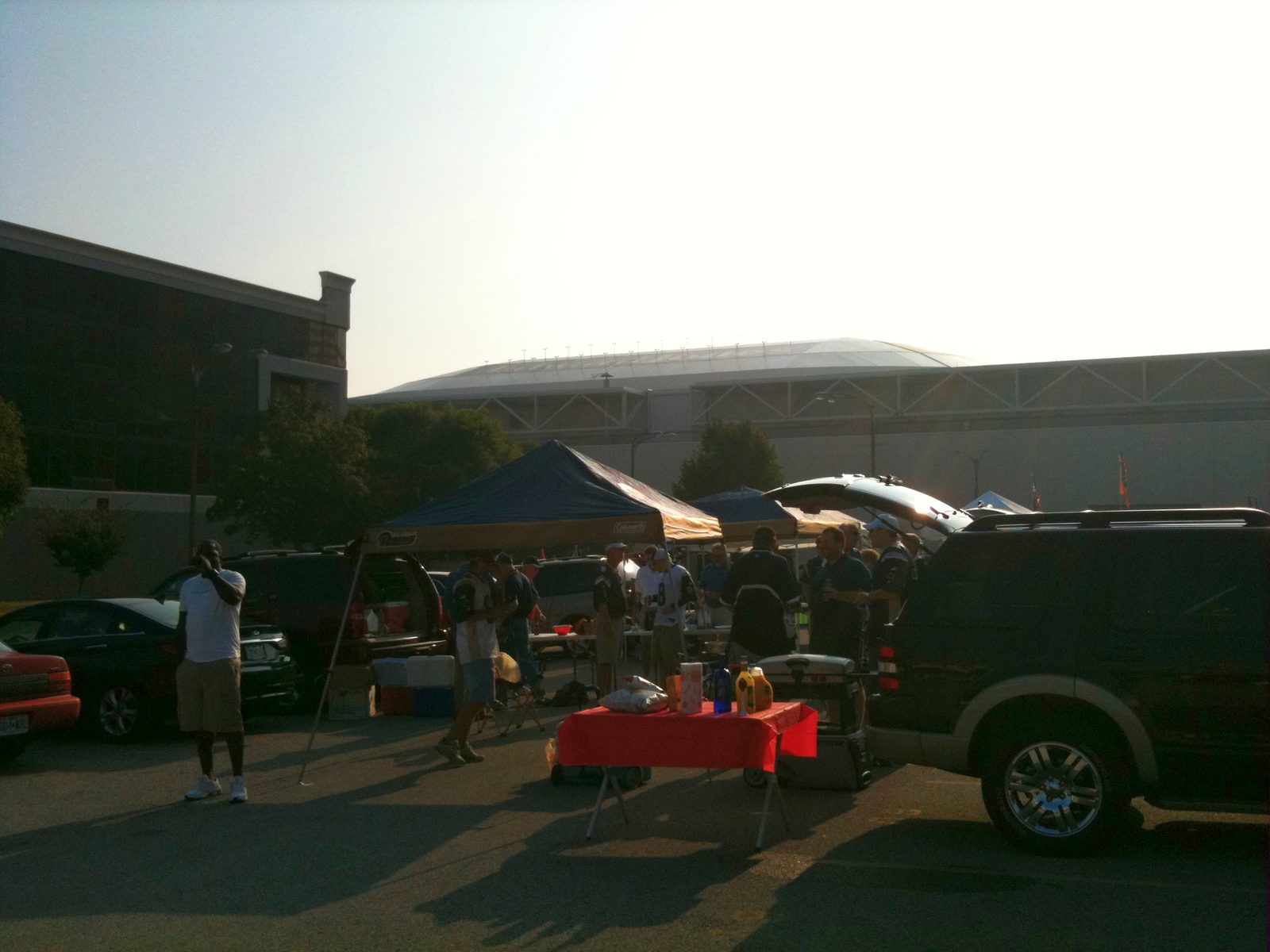 Pop-up tents and a folding table on asphalt with the stadium in the background